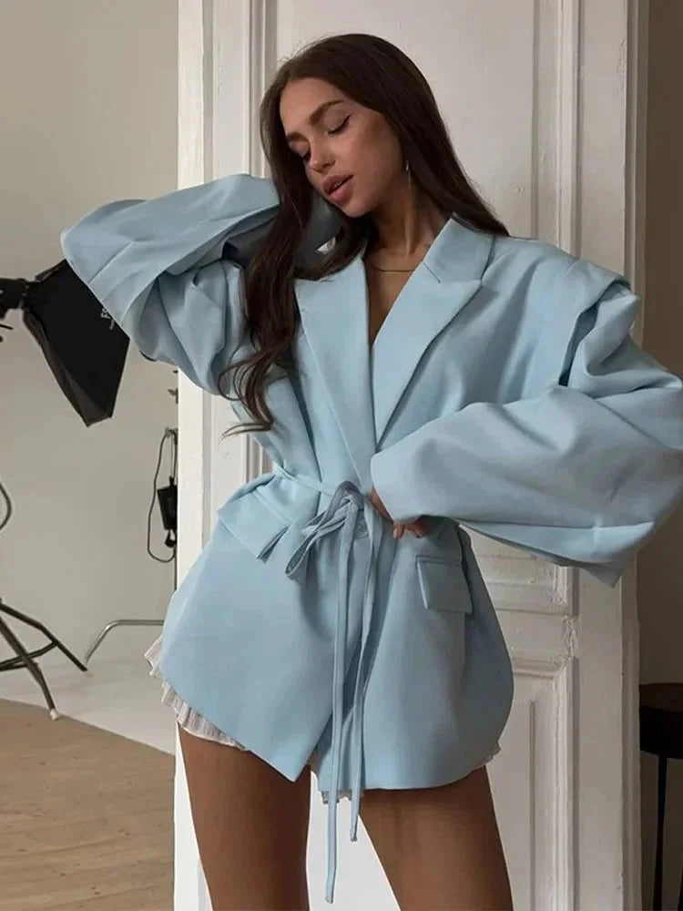 Blazer rose pour femme avec laçage, épaulettes et coupe cintrée.