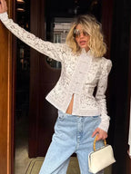 Blouse en dentelle blanche, col montant, manches longues, motif délicat et détails raffinés.