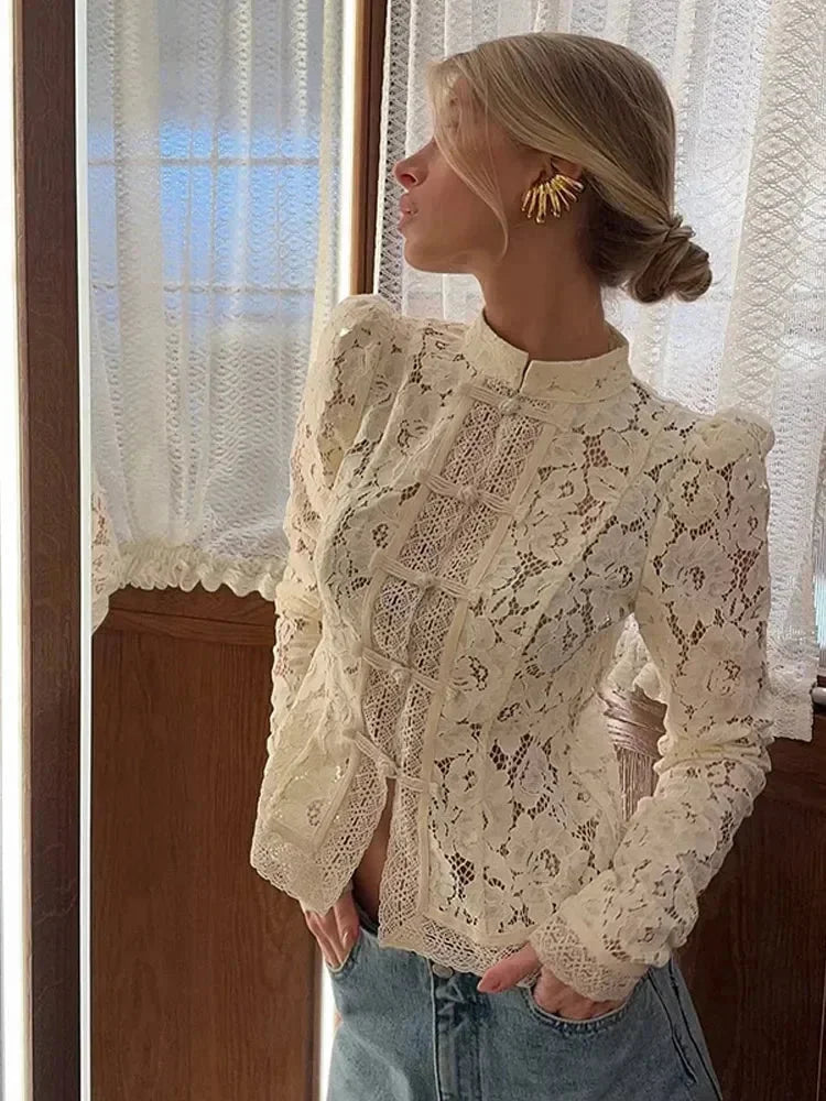 Blouse en dentelle noire à col montant et manches longues, conçue pour des occasions élégantes.