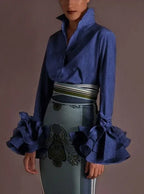 Blouse femme bleue avec manches volantées, en tissu léger, adaptée pour des occasions élégantes et décontractées.