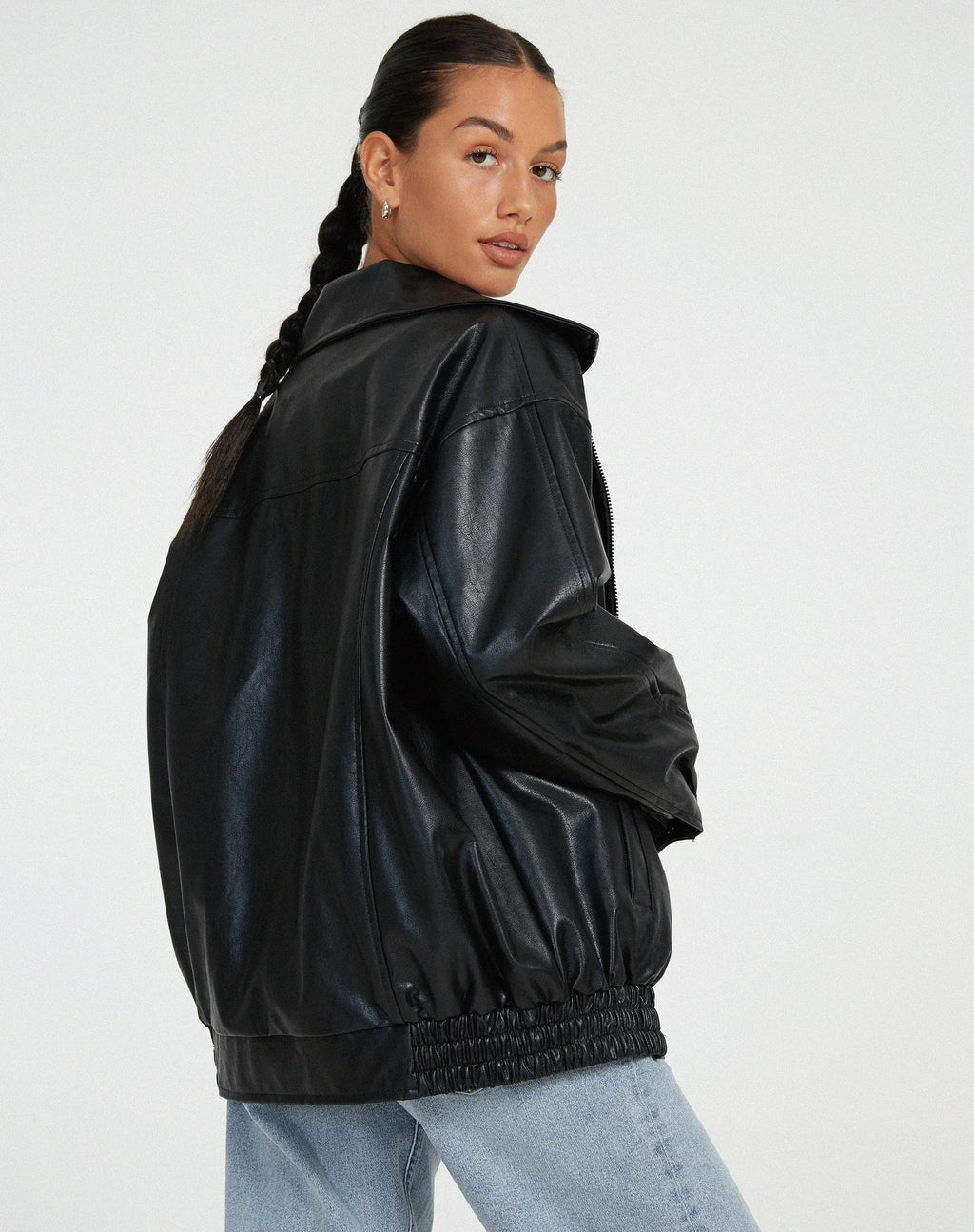 Blouson femme noir en similicuir, style motard, avec zip asymétrique et détails en clous.