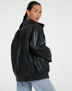 Blouson femme noir en similicuir, style motard, avec zip asymétrique et détails en clous.