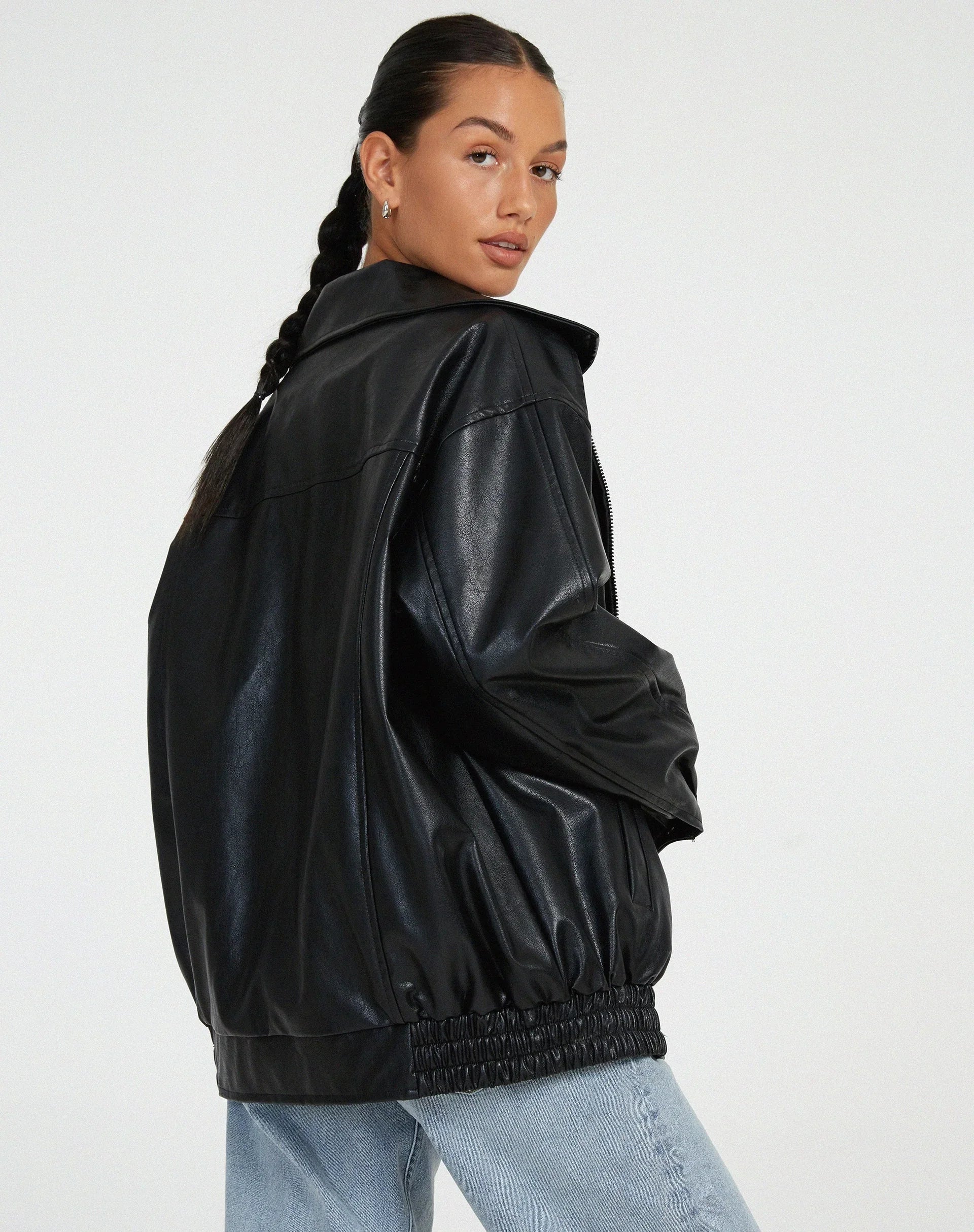 Blouson femme noir en similicuir, style motard, avec zip asymétrique et détails en clous.