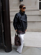 Blouson noir pour femme en matériau résistant, col montant et design moderne et minimaliste.