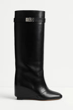 Bottes hautes en simili cuir noir avec fermeture décorative et talon élevé.