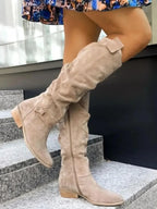 Bottes hautes pour femme en cuir beige, à talon bas, offrant un design confortable et élégant.