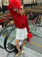 Cardigan femme rouge avec manches plumes et boutons, en tissu doux, pour un confort élégant.