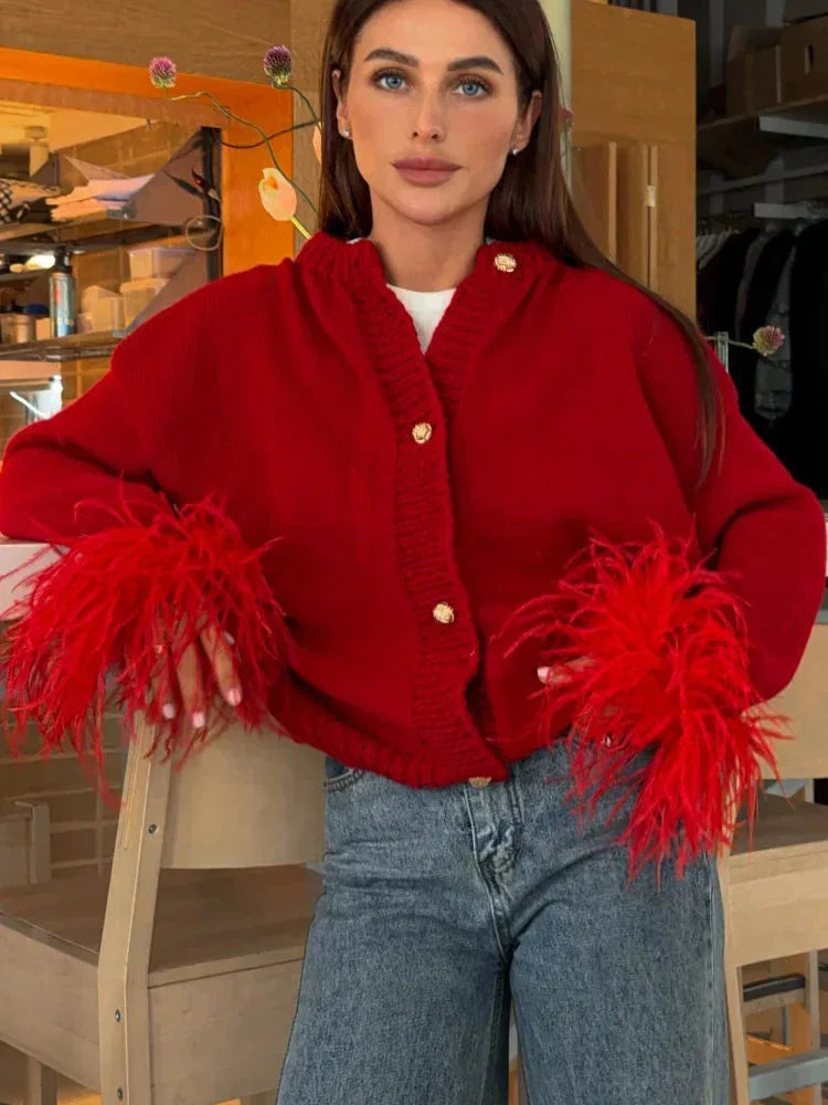 Cardigan femme rouge avec manches en plumes et boutons, en tissu doux, adapté pour des occasions décontractées ou habillées.
