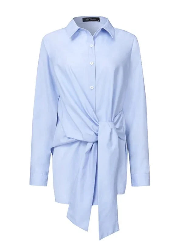 Chemise blanche pour femme en tissu léger, ajustable avec ceinture nouée à la taille.