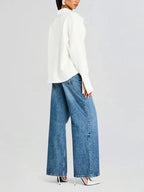 Chemise fluide blanche cassée pour femme, en matière légère, avec une boutonnière et un design décontracté.