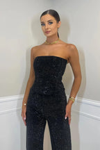 Combinaison noire femme avec bustier et jambes larges en tissu léger et fluide.