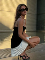 Ensemble bustier noir et jupe plissée blanche, tissu doux, haut sans bretelles ajusté, idéal pour une soirée élégante.