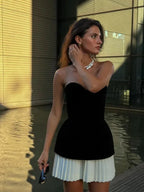 Ensemble bustier noir avec jupe plissée blanche, haut sans bretelles en tissu léger et ajusté, idéal pour soirées élégantes.