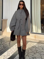 Ensemble gris femme avec jupe courte et veste longue sans manches en tissu léger.