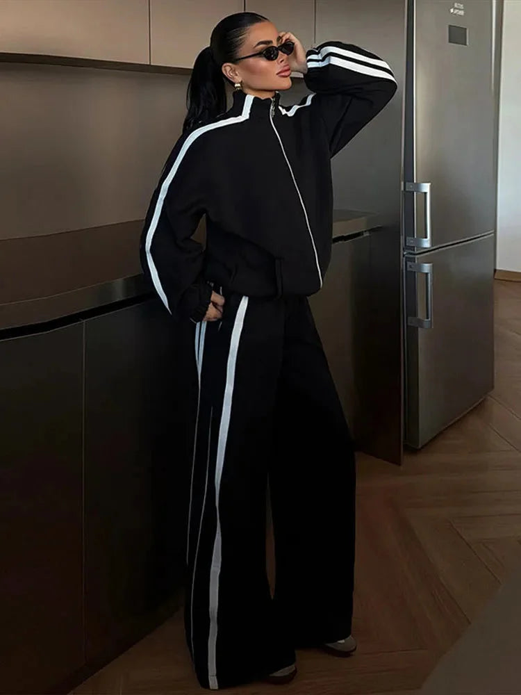 Ensemble de sport femme blanc, comprenant une veste zippée et un pantalon large en tissu respirant.