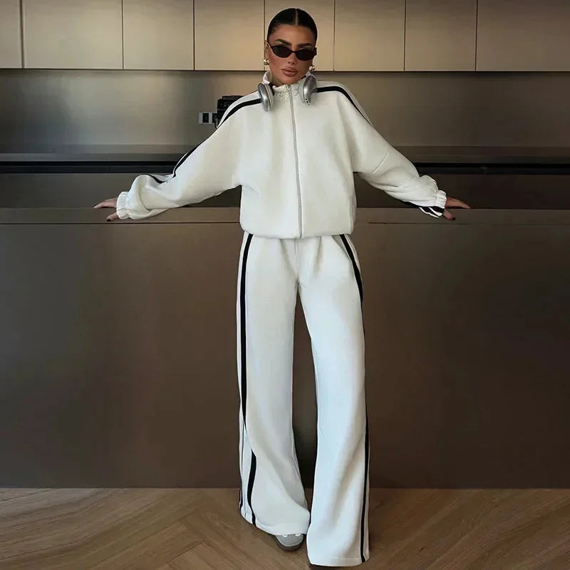 Ensemble sport femme noir, composé d'une veste zippée et d'un pantalon large en tissu respirant.