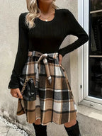 Haut ajusté noir en coton avec manches longues, associé à une jupe évasée à carreaux en tissu léger.