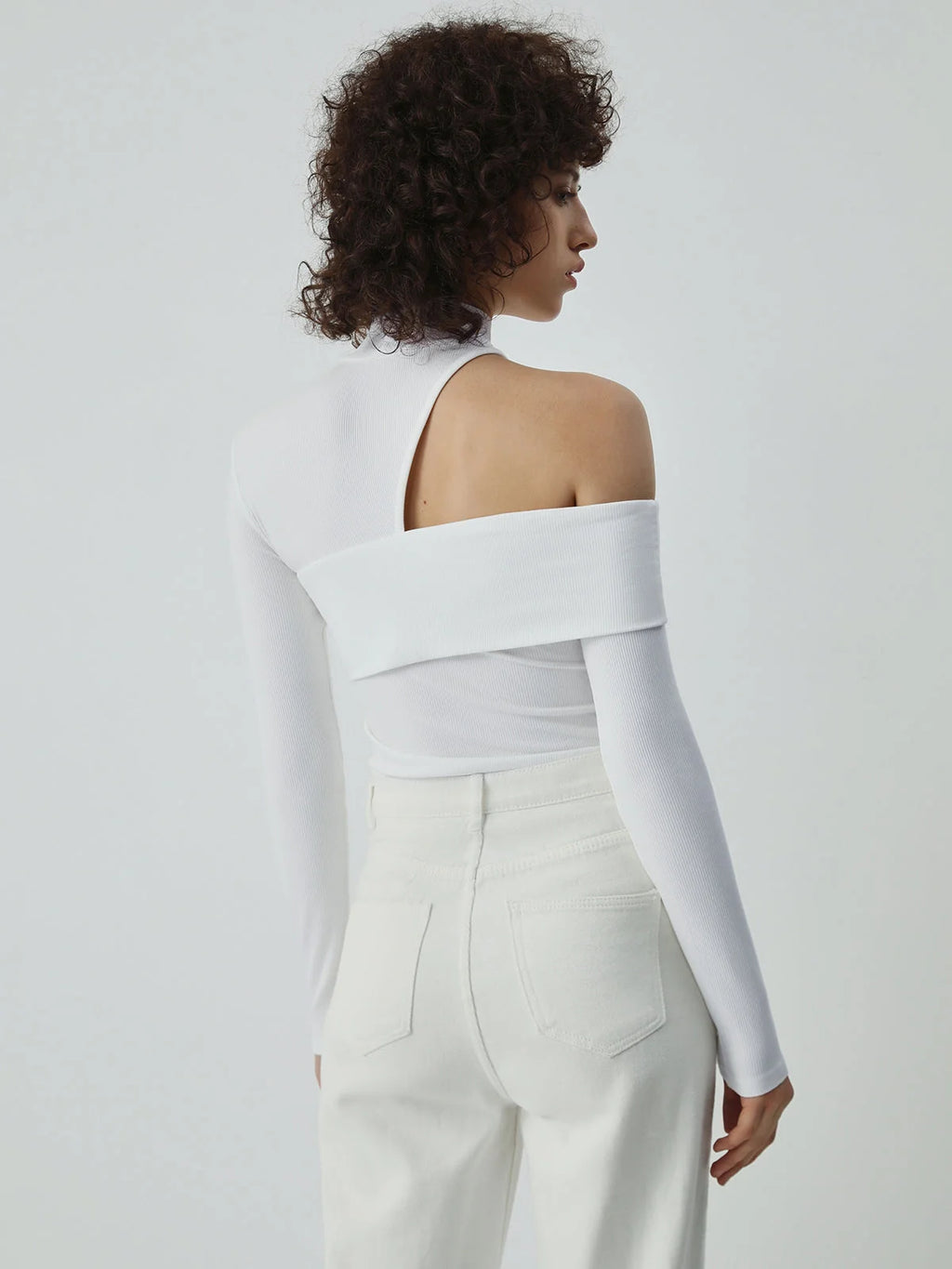 Haut femme blanc asymétrique avec col montant et découpe, en tissu doux et extensible.
