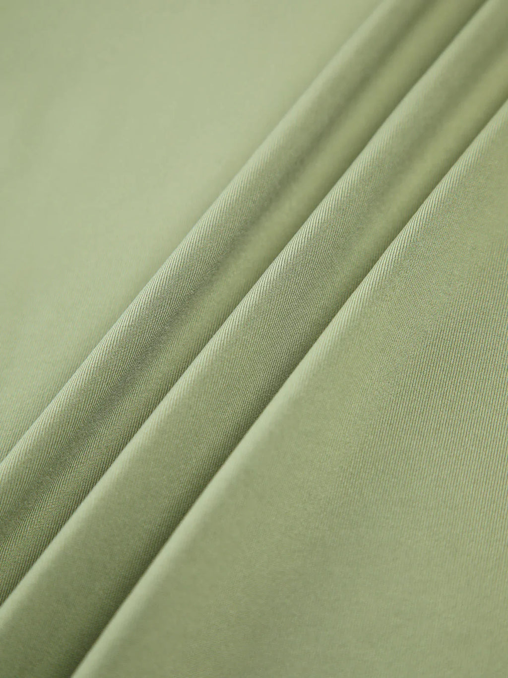 Haut femme vert clair à manches longues, en tissu extensible, avec un design ajusté et moderne.