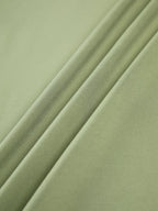 Haut femme vert clair à manches longues, en tissu extensible, avec un design ajusté et moderne.