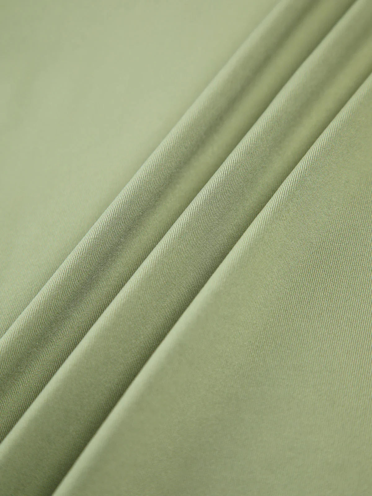 Haut femme vert clair à manches longues, en tissu extensible, avec un design ajusté et moderne.