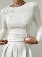 Haut à manches longues en coton doux, avec coutures détaillées et design moderne, couleur blanche.