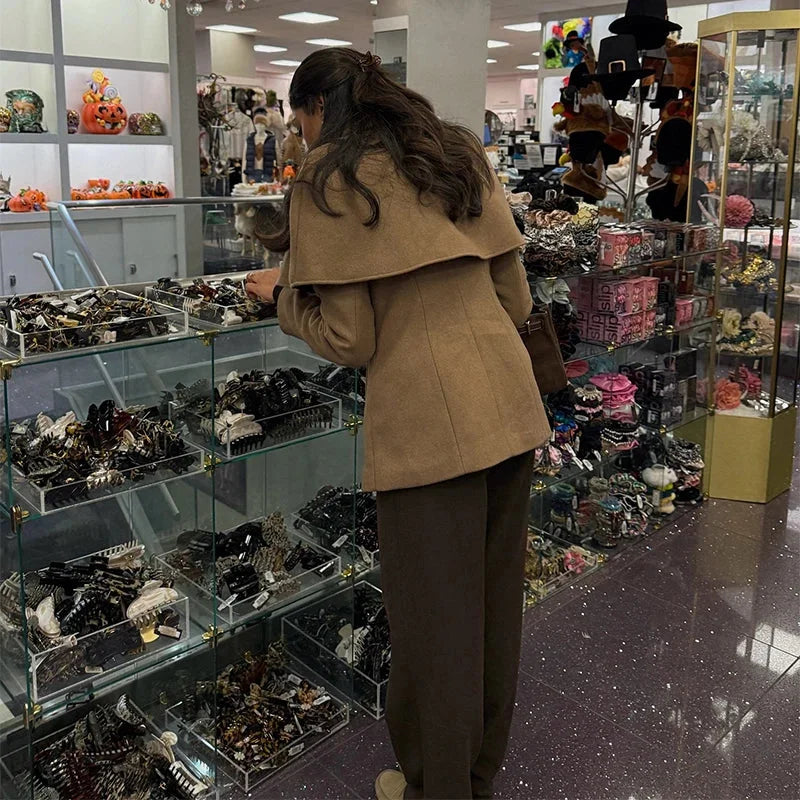 Manteau femme camel avec cape, taille ajustée, design structuré et capuche en matériau doux.