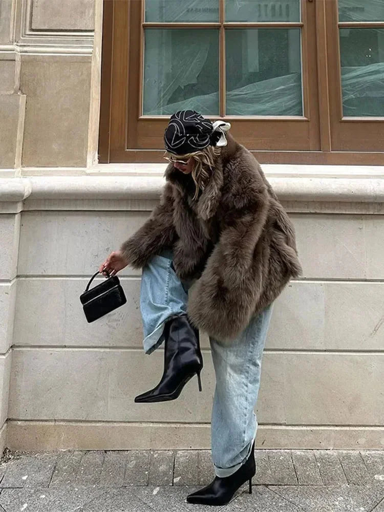 Brauner Damenmantel aus Kunstfell mit langen Ärmeln, weichem Material und zeitlosem Design für stilvolle Herbsttage.