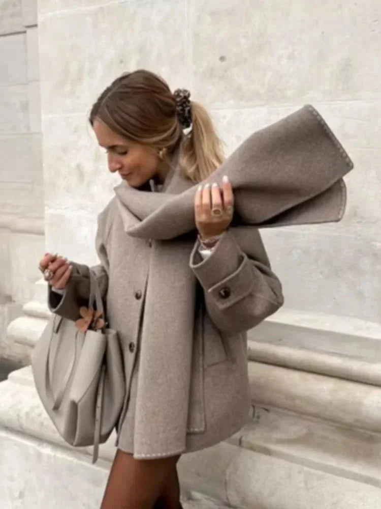 Manteau femme taupe avec écharpe, boutons décoratifs et coupe élégante pour des tenues variées.