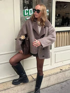 Manteau in taupe mit Teddy-Kragen, Knopfdetails und weichem Material für modischen Komfort in der kalten Jahreszeit.