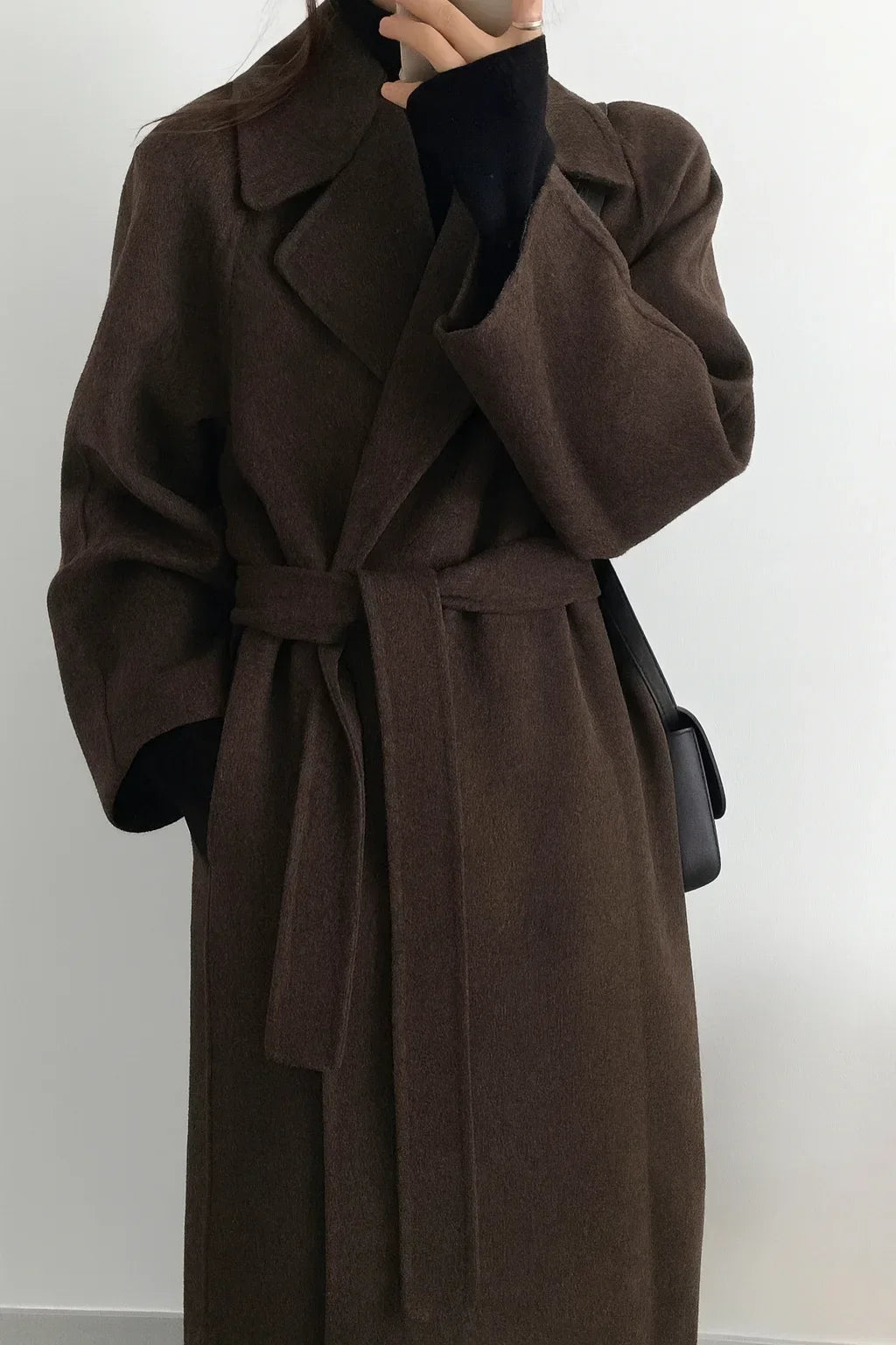 Manteau long marron pour femme avec ceinture et col chic, en tissu doux et chaud pour les journées fraîches.