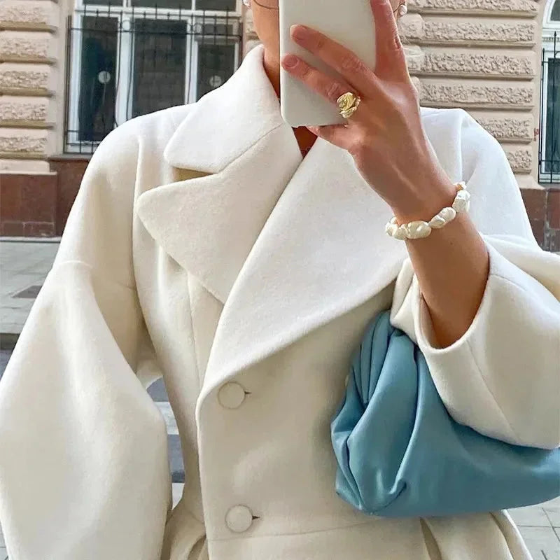 Weißer langer Mantel für Damen aus hochwertigem Stoff mit weitem Kragen und elegantem, schlichten Schnitt.