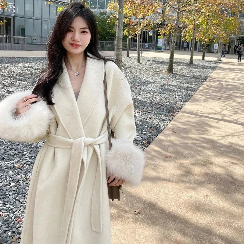 Langmantel für Damen mit Gürtel, aus warmem Material, verziert mit eleganten Kunstfellärmeln und modischem Schnitt.