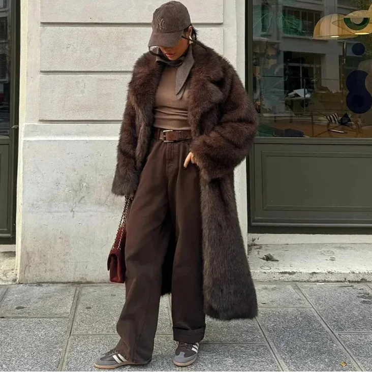 Manteau long femme en fausse fourrure marron, avec capuche amovible et poches latérales.