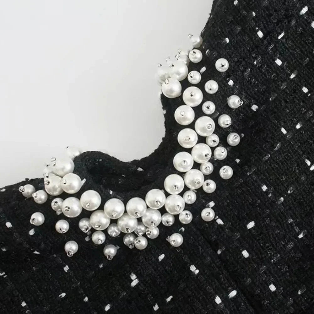 Mini robe noire perlée avec découpes, manches épaules nues, en tissu léger, idéal pour les soirées et événements.