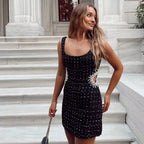 Mini robe noire en tissu léger, perlée, avec découpes et manches épaules nues, idéale pour les soirées et événements.