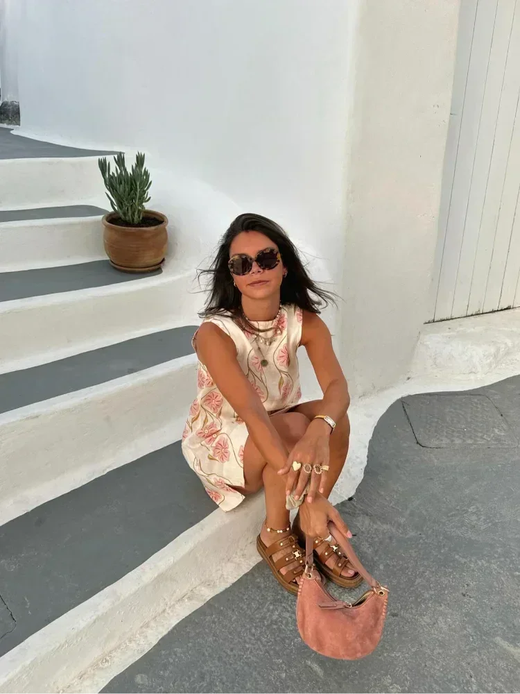 Mini robe sans manches en tissu léger blanc avec motifs de fleurs roses, idéale pour les journées d'été.