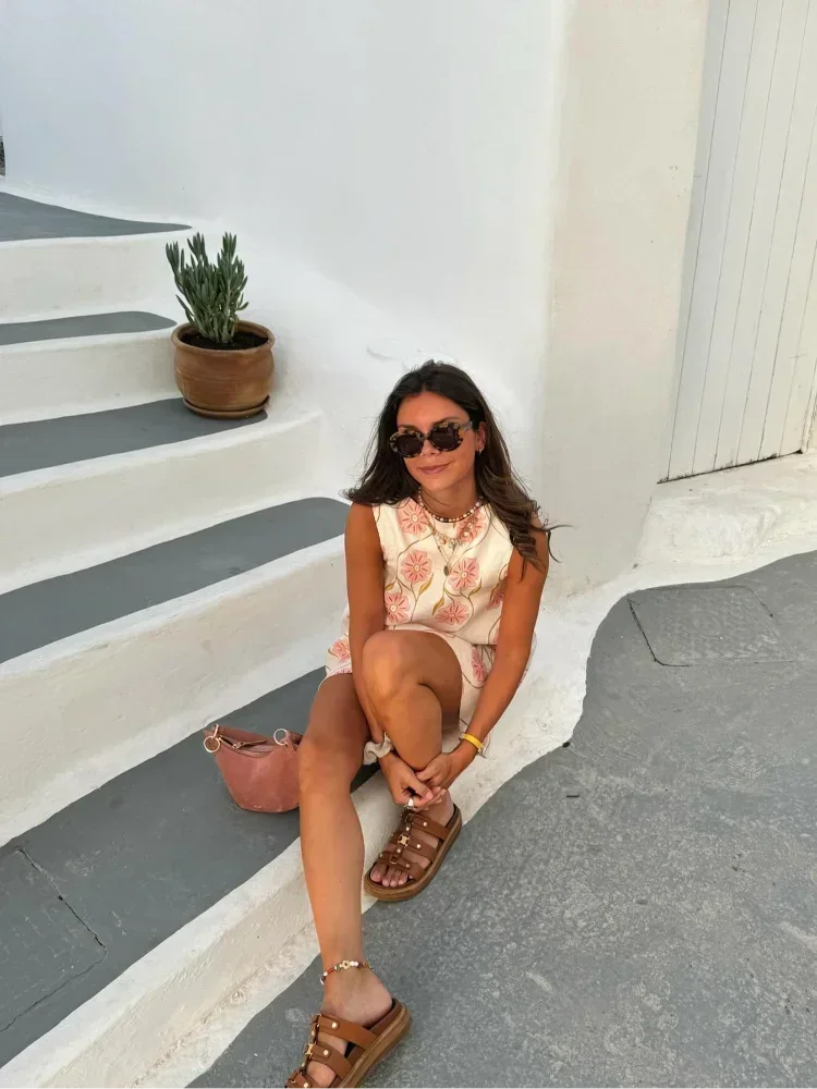 Mini robe sans manches en tissu léger, blanche avec un motif de fleurs roses, idéale pour les journées d'été.