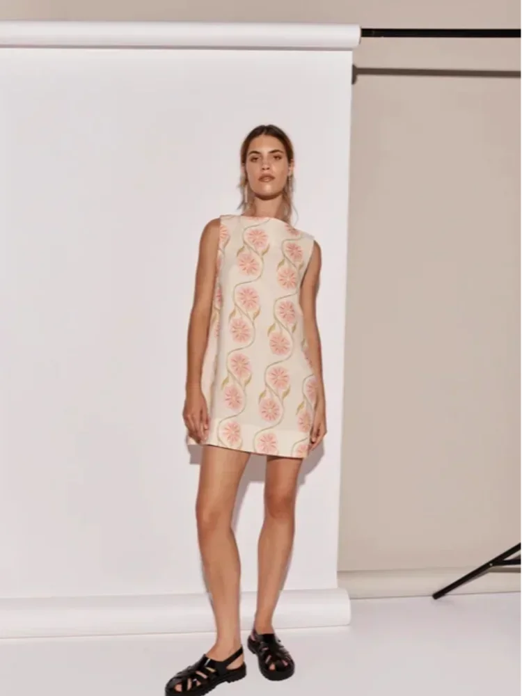 Mini robe sans manches en tissu léger blanc avec motif de fleurs roses, idéale pour un look estival frais et élégant.