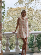 Mini robe sans manches en tissu léger blanc avec imprimé de fleurs roses, idéale pour des journées d'été.