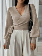 Pull cache-cœur beige pour femme en tricot doux, avec ceinture à nouer et décolleté en V.