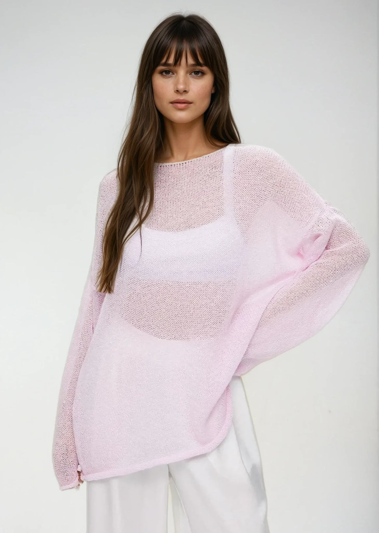 Pull femme léger en maille transparente rose, avec un design décontracté et des manches amples.