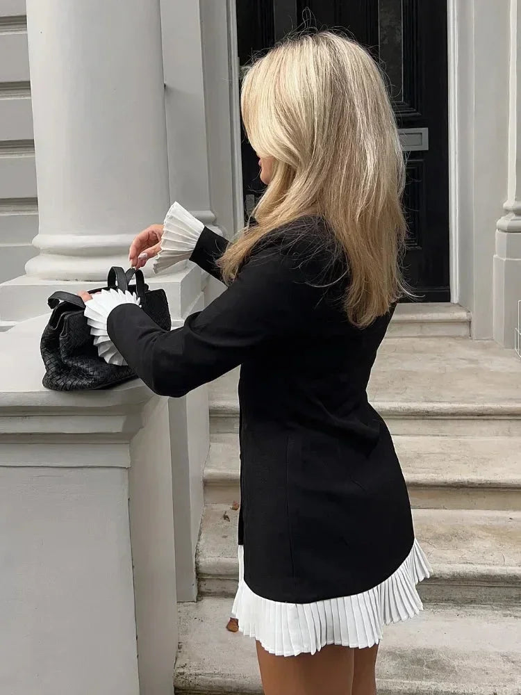 Robe blazer courte noire en tissu léger avec ourlet plissé blanc et manches longues, idéale pour le bureau ou les soirées.