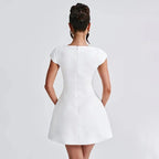 Robe courte blanche en coton avec encolure carrée et manches courtes, silhouette ajustée pour soirée élégante.
