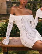 Robe courte en dentelle blanche avec épaules dénudées, ornée de motifs floraux délicats et d'une coupe ajustée.