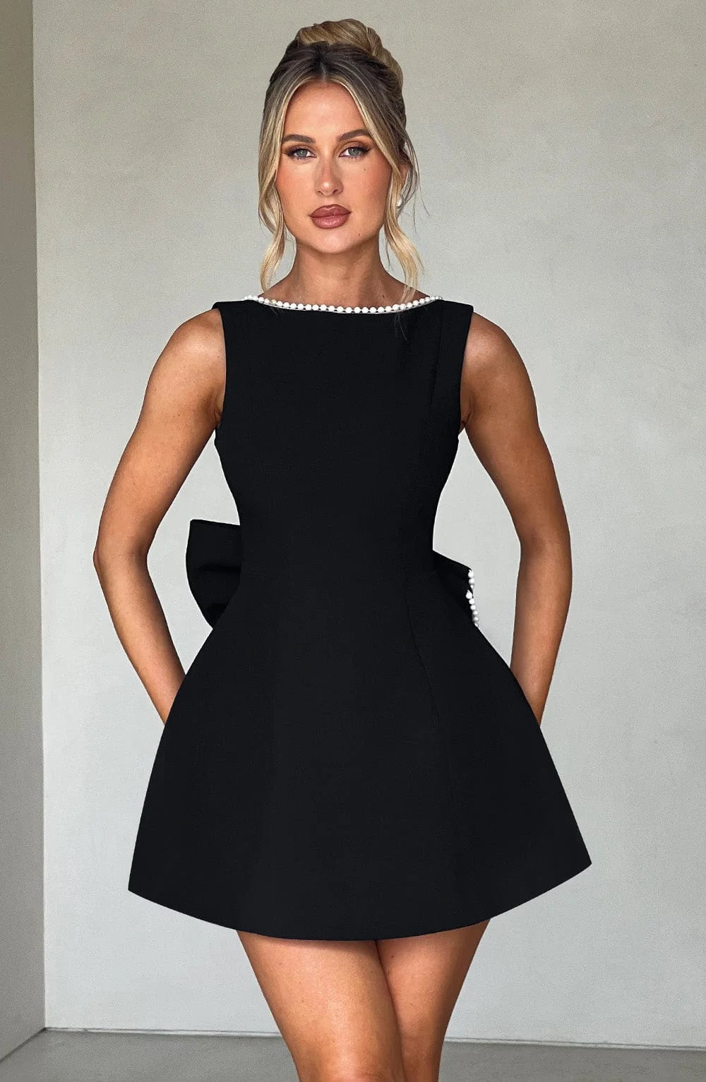 Robe courte en tissu léger avec nœud décoratif au dos et coupe ajustée, parfaite pour un look élégant et décontracté.