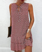 Robe courte sans manches, en tissu léger, imprimée de motifs graphiques, col noué et volants, idéale pour l'été à la plage.
