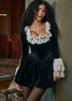 Robe courte noire en dentelle, manches longues voluminues, col carré, idéale pour des soirées élégantes.