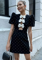 Robe courte à pois avec nœuds et manches bouffantes, confectionnée en polyester léger pour une soirée élégante.