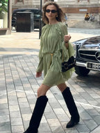 Robe courte sage avec volants, manches longues, en tissu léger et fluide, idéale pour les soirées d'été.